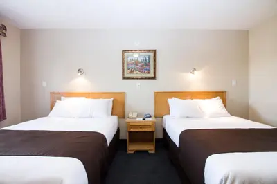 a hotel room with two beds and a picture on the wall at West Country Inn in Drayton Valley