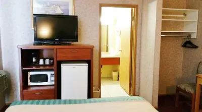 a room with a television on a cabinet with a microwave at Alpine Motel in Kamloops