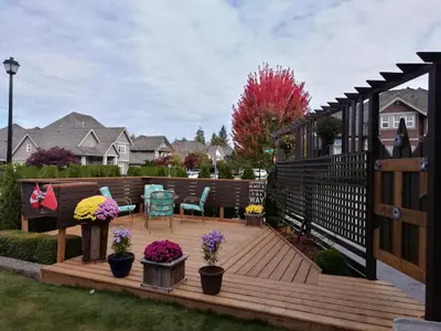 a wooden deck with chairs and flowers in a yard at Sunny Island by White Rock B&B in White Rock