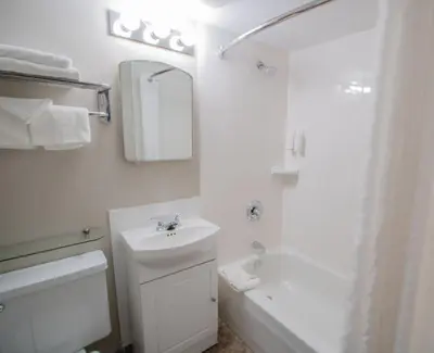 a white bathroom with a sink and a mirror at Scott's Inn & Suites in Kamloops