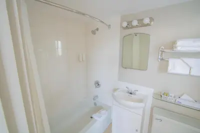 a white bathroom with a shower and a sink at Scott's Inn & Suites in Kamloops