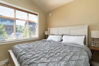 a bedroom with a large bed with a large window at Avatar by Eagle Reach Properties in Port Renfrew