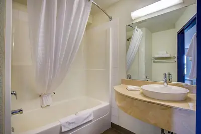 a bathroom with a sink and a tub and a mirror at Motel 6-Grande Prairie, AB in Grande Prairie