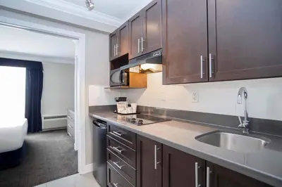 a kitchen with wooden cabinets and a sink at Sandman Signature Prince George Hotel in Prince George