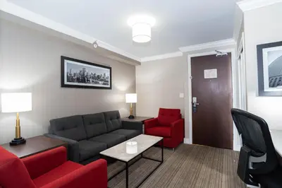 a living room with a couch and red chairs at Sandman Hotel & Suites Calgary South in Calgary