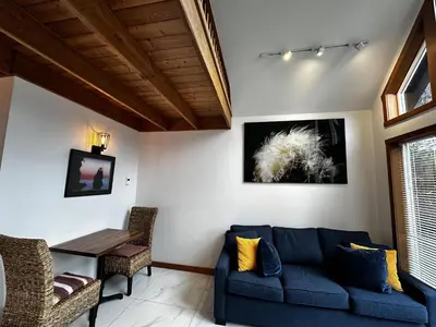 a living room with a blue couch and a table at Private Oceanfront Cabin And Hot Tub! - Gww in Ucluelet