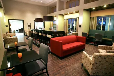 a restaurant with a red couch and tables and chairs at Hampton Inn & Suites Red Deer in Red Deer