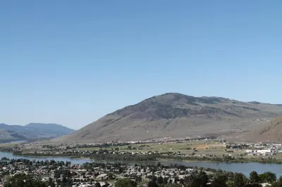 a town on a river with a mountain in the background at Knights Inn Kamloops in Kamloops