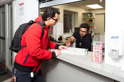 two men standing at a counter looking at a map at HI Edmonton - Hostel in Edmonton