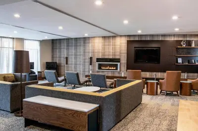 a lobby with a waiting area with chairs and a fireplace at Courtyard by Marriott Edmonton West in Edmonton