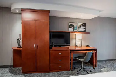 a room with a desk with a television and a cabinet at Courtyard by Marriott Edmonton West in Edmonton
