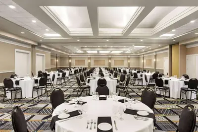 a banquet hall with white tables and chairs at Royal Hotel Edmonton Airport Trademark Collection By Wyndham in Leduc