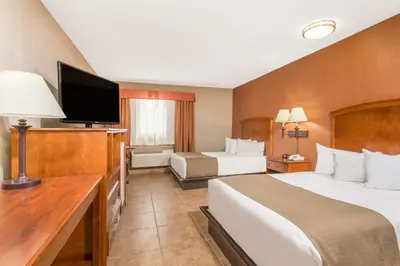 a hotel room with two beds and a flat screen tv at Canmore Inn & Suites in Canmore