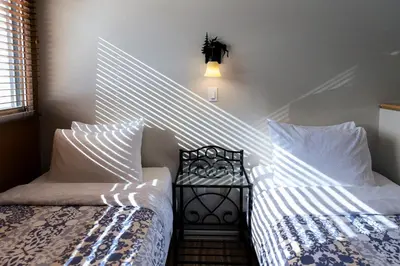 a bedroom with two beds with white sheets and a side table at Astoria Hotel in Jasper