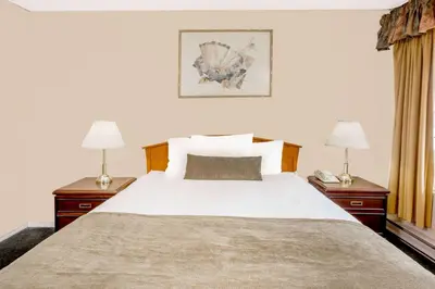 a bedroom with a large white bed with two lamps at Howard Johnson by Wyndham Downtown Kamloops in Kamloops