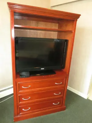 a wooden entertainment center with a flat screen tv at Tropicana Suite Hotel in Vancouver