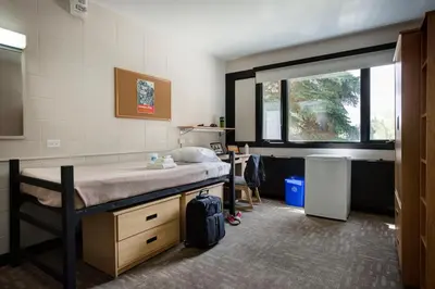 a room with a bed and a desk and a window at University of Calgary Accommodations and Events in Calgary