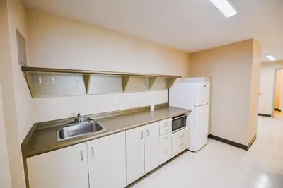 a kitchen with white cabinets and a sink and a refrigerator at Residence & Conference Centre - Kamloops in Kamloops