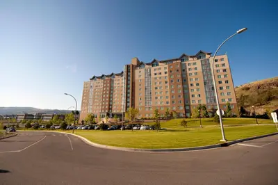 a large apartment building with a park in front of it at Residence & Conference Centre - Kamloops in Kamloops