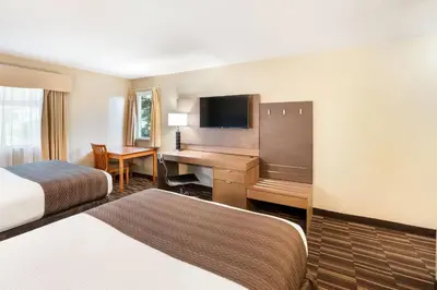 a hotel room with two beds and a desk at Days Inn by Wyndham Nanaimo in Nanaimo