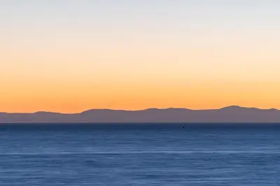 a sunset over the ocean with mountains in the background at Ocean Promenade Hotel in White Rock