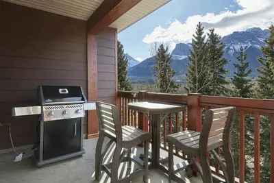 a balcony with a stove and a table and chairs at Mountain View Escape with open hot tub, Views!! in Canmore