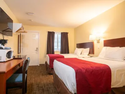 a hotel room with two beds and a desk at Kings Motor Inn in Kamloops