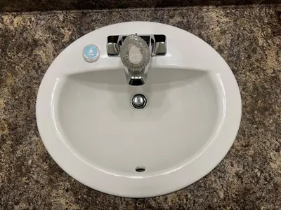 a white bathroom sink with a clock on it at Kings Motor Inn in Kamloops