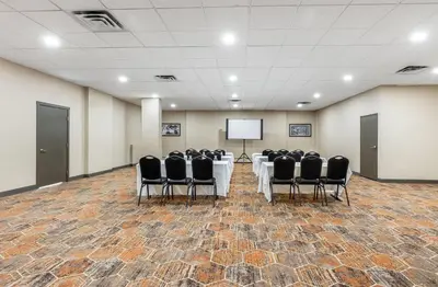 a conference room with a table and chairs and a screen at Days Inn by Wyndham Airdrie in Airdrie