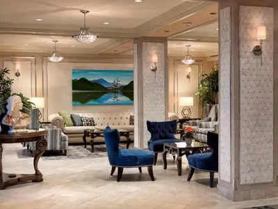 a lobby with blue chairs and a living room at Chateau Victoria Hotel & Suites in Victoria