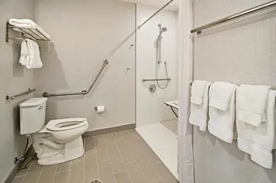 a bathroom with a toilet and a shower with towels at Holiday Inn Hotel & Suites - Calgary Airport North by IHG in Calgary
