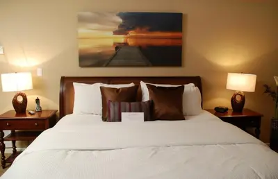 a bedroom with a bed with two lamps and a painting at Rosellen Suites at Stanley Park in Vancouver