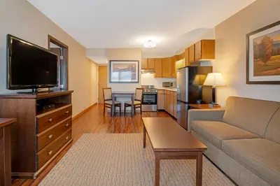 a living room with a couch and a tv and a kitchen at Best Western Plus Emerald Isle Hotel in Sidney