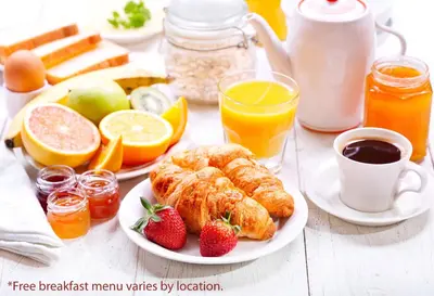 a breakfast table with croissants and fruit and juice at Days Inn & Suites by Wyndham Langley in Langley