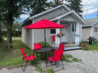 a table and chairs with a red umbrella in front of a house at Brookside Motel in Golden