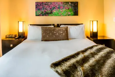 a bedroom with a large white bed with two lamps at Silver Creek Lodge in Canmore