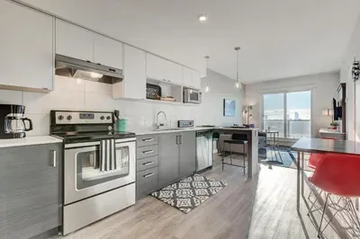 a large kitchen with stainless steel appliances and a table at Marquee on 16th in Calgary
