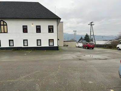 a white building with cars parked in a parking lot at Char's Landing Hostel in Port Alberni