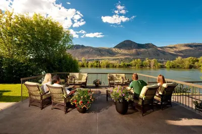 a group of people sitting on a deck with a view of a river at Riverland Inn & Suites in Kamloops