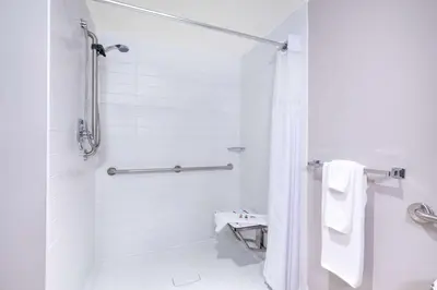 a white bathroom with a shower and a toilet at Microtel Inn & Suites by Wyndham Fort McMurray in Fort McMurray