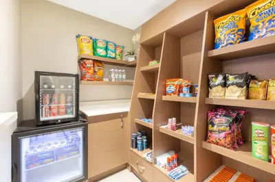 a room with a refrigerator and shelves with snacks at Microtel Inn & Suites by Wyndham Fort McMurray in Fort McMurray