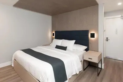 a bedroom with a large white bed with a blue headboard at Harrison Beach Hotel in Harrison Hot Springs