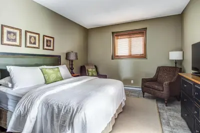 a bedroom with a bed and a chair and a television at Bighorn Meadows Resort in Radium Hot Springs