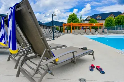 a lounge chair and flip flops next to a swimming pool at Bighorn Meadows Resort in Radium Hot Springs