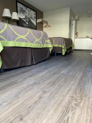 a room with two beds and a wooden floor at Sage Inn Merritt BC in Merritt