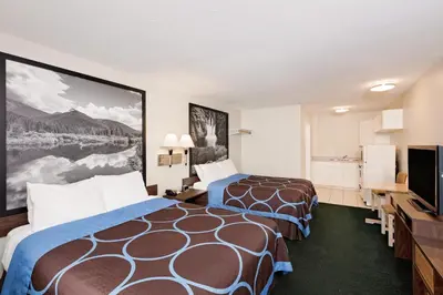 a hotel room with two beds and a flat screen tv at Sage Inn Merritt BC in Merritt