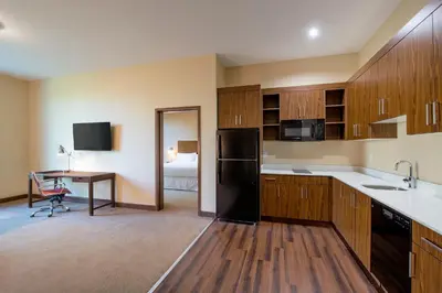 a kitchen with a black refrigerator and a table at Four Points by Sheraton Grande Prairie in Grande Prairie