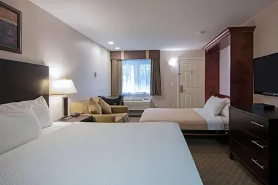 a hotel room with two beds and a couch at Travelodge by Wyndham Kamloops Mountview in Kamloops
