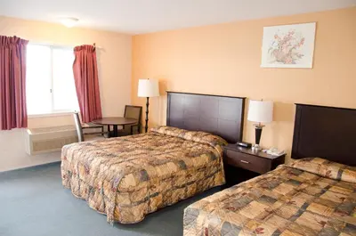 a hotel room with two beds and a table at Best Budget Inn & Suites Kamloops in Kamloops