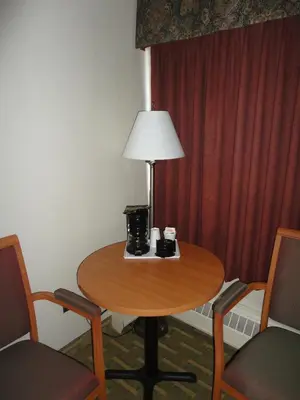 a table in a room with a lamp and chairs at Travelodge by Wyndham Edmonton East in Edmonton